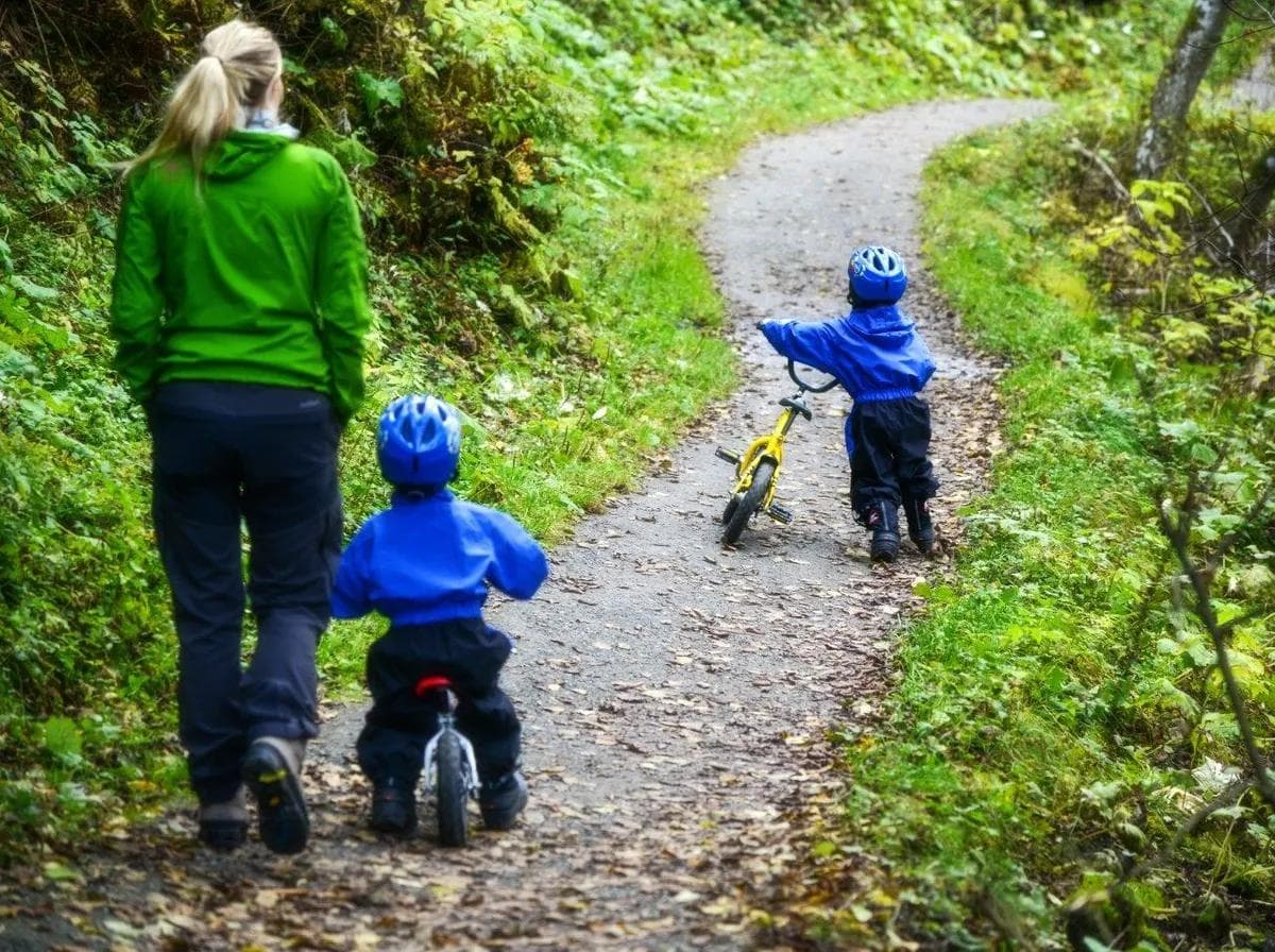 En voksen dame med to babyer på sykkel.